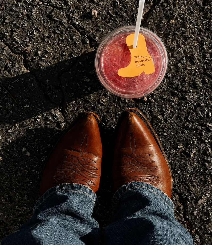 Cowboy boots and a strawberry lemonade on asphalt