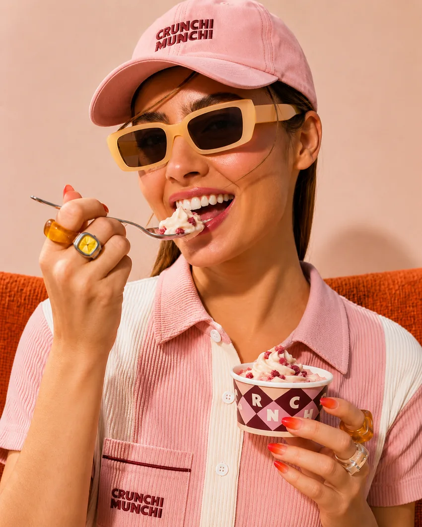Smiling customer in a Crunchi Munchi cap eating frozen yogurt