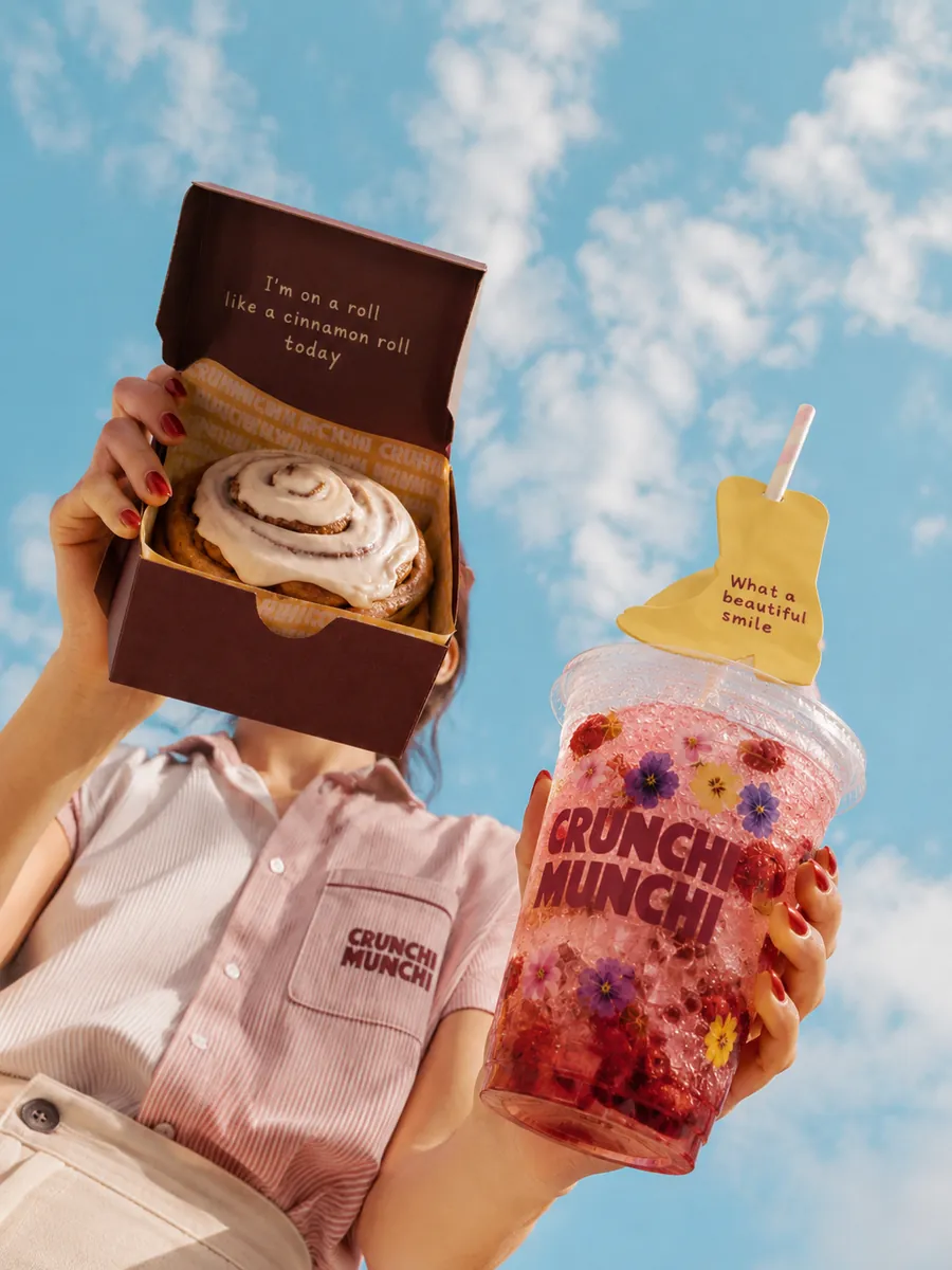 Holding a cinnamon roll box and a flower lemonade up against the Texas sky